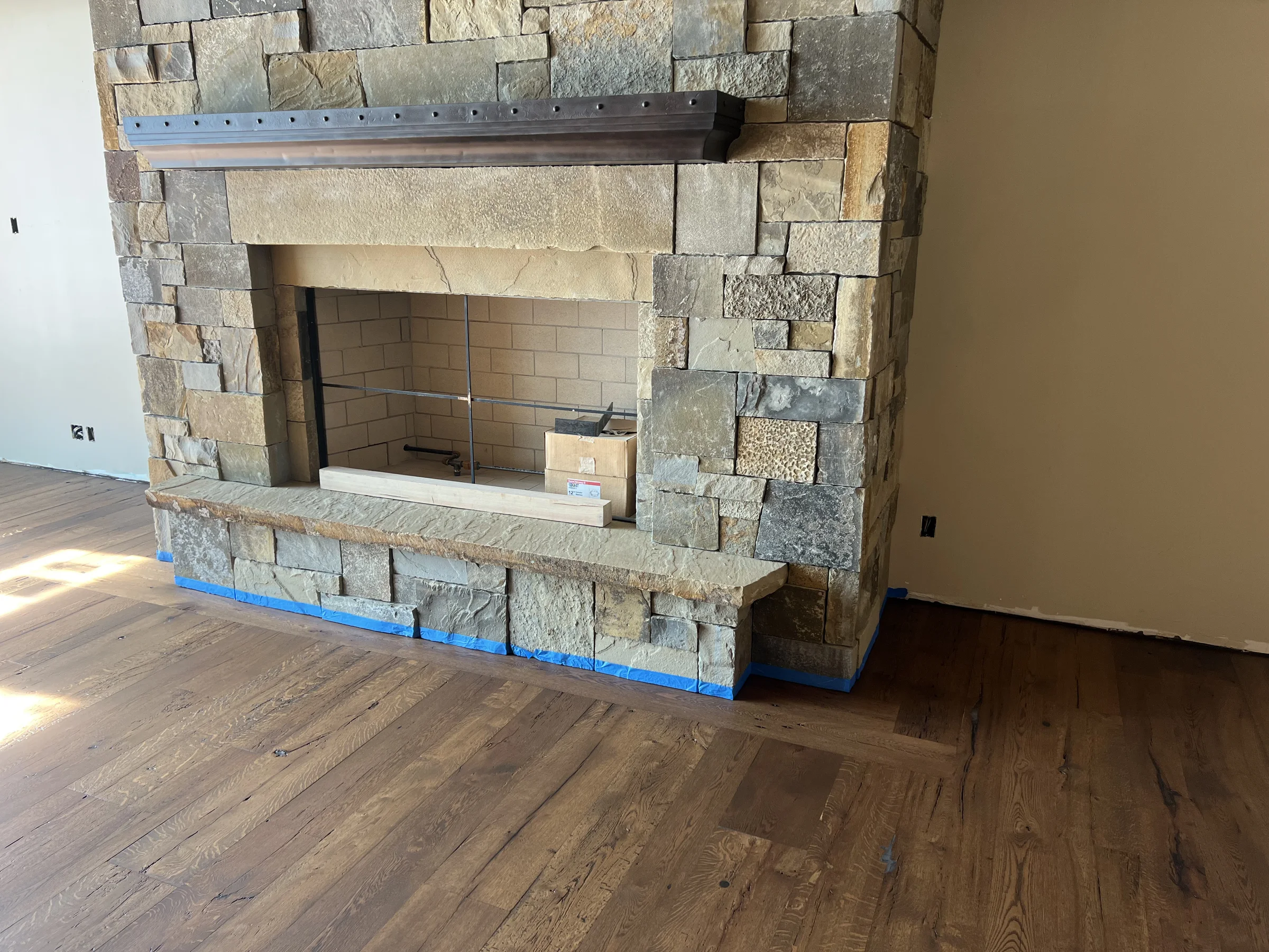 Stone fireplace and wide-plank hardwood floor in the living room of a Missoula featured project