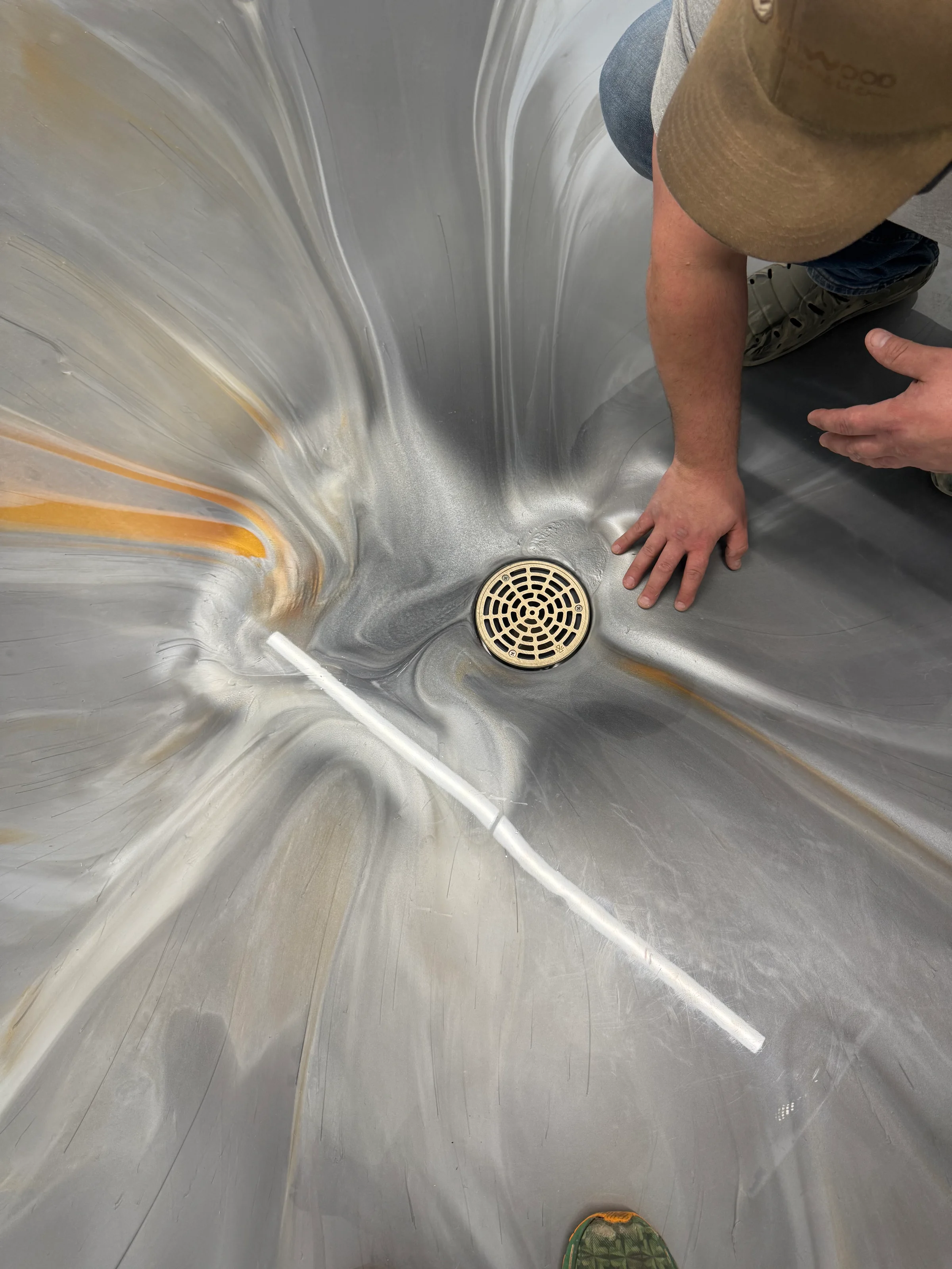 Winnwood Resins technician hand-finishing a metallic epoxy floor around a drain